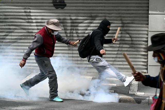 A miner kicks away a tear gas canister thrown by riot police during a protest demanding the resignation of Bolivian President Rodrigo Paz, in La Paz, on May 18, 2026. Bolivians have taken to the streets for the past two weeks, blocking roads into La Paz and disrupting deliveries of food, medicine and other goods to the seat of government, while demanding higher wages, economic relief and the resignation of centre-right President Rodrigo Paz amid a severe economic crisis. (Photo by AIZAR RALDES / AFP)