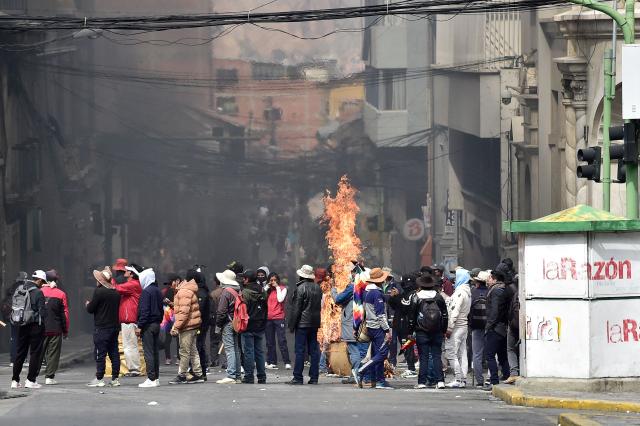 Flames rise from a cardboard box as miners clash with riot police during a protest demanding the resignation of Bolivian President Rodrigo Paz, in La Paz, on May 18, 2026. Bolivians have taken to the streets for the past two weeks, blocking roads into La Paz and disrupting deliveries of food, medicine and other goods to the seat of government, while demanding higher wages, economic relief and the resignation of centre-right President Rodrigo Paz amid a severe economic crisis. (Photo by Jorge BERNAL / AFP)