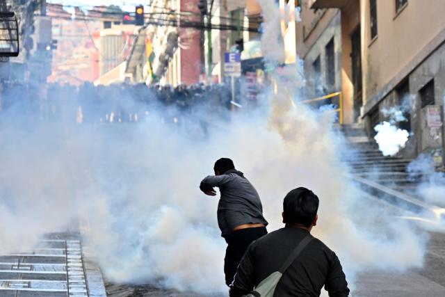 Riot police fire tear gas to demonstrators during a protest demanding the resignation of Bolivian President Rodrigo Paz, in La Paz, on May 18, 2026. Bolivians have taken to the streets for the past two weeks, blocking roads into La Paz and disrupting deliveries of food, medicine and other goods to the seat of government, while demanding higher wages, economic relief and the resignation of centre-right President Rodrigo Paz amid a severe economic crisis. (Photo by Aizar RALDES / AFP)