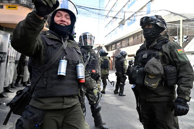 Riot police take position during clashes with demonstrators during a protest demanding the resignation of Bolivian President Rodrigo Paz, in La Paz, on May 18, 2026. Bolivians have taken to the streets for the past two weeks, blocking roads into La Paz and disrupting deliveries of food, medicine and other goods to the seat of government, while demanding higher wages, economic relief and the resignation of centre-right President Rodrigo Paz amid a severe economic crisis. (Photo by Aizar RALDES / AFP)
