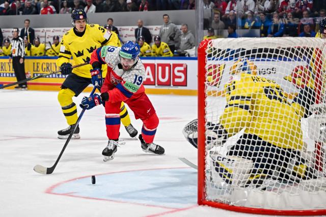 Czech Republic's forward #19 Jakub Flek (C) controls the puck next to Sweden's goalkeeper #45 Magnus Hellberg (R) during the Group B ice hockey match between Sweden and Czech Republic at the IIHF Ice Hockey Men's World Championship at BFC Arena in Fribourg on May 18, 2026. (Photo by Fabrice COFFRINI / AFP)