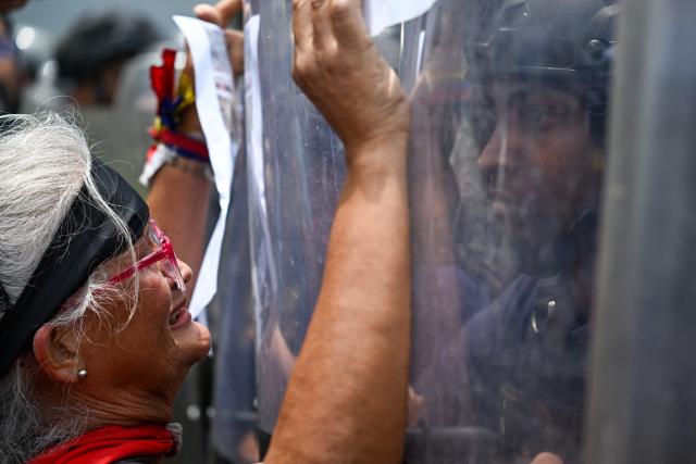 A woman confronts Bolivarian National Police (PNB) officers during a protest following the death of Carmen Navas, the mother of late political prisoner Victor Quero Navas, in Caracas, on May 18, 2026. The mother of Venezuelan political prisoner Victor Hugo Quero Navas died on May 17, 2026 at age 81, just days after confirming the death of her son in state custody, her relatives told AFP. (Photo by Juan BARRETO / AFP)