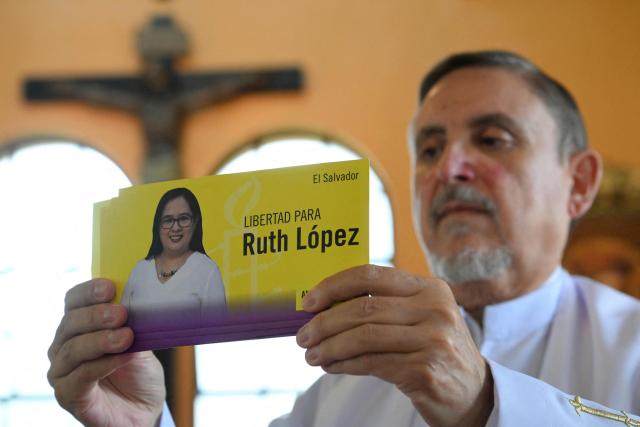 Priest Miquel Cortes holds a sticker during a religious ceremony in honour of Salvadoran lawyer Ruth Lopez at the chapel of Rafael Landнvar University in Guatemala City on May 18, 2026, who marked one year in detention in El Salvador. The NGO Cristosal demanded proof regarding the health of Salvadoran lawyer Ruth Lopez, who was arrested a year ago after reporting alleged corruption cases in Nayib Bukele’s government and who is being denied family visits. (Photo by JOHAN ORDONEZ / AFP)