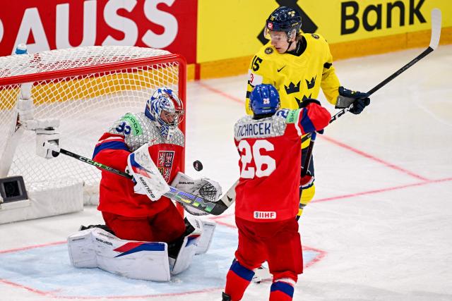 Czech Republic's goalkeeper #32 Josef Korenar makes a save next to Czech Republic's defender #26 Jiri Tichacek (front) and Sweden's forward #15 Jack Berglund (R) during the Group B ice hockey match between Sweden and Czech Republic at the IIHF Ice Hockey Men's World Championship at BFC Arena in Fribourg on May 18, 2026. (Photo by Fabrice COFFRINI / AFP)