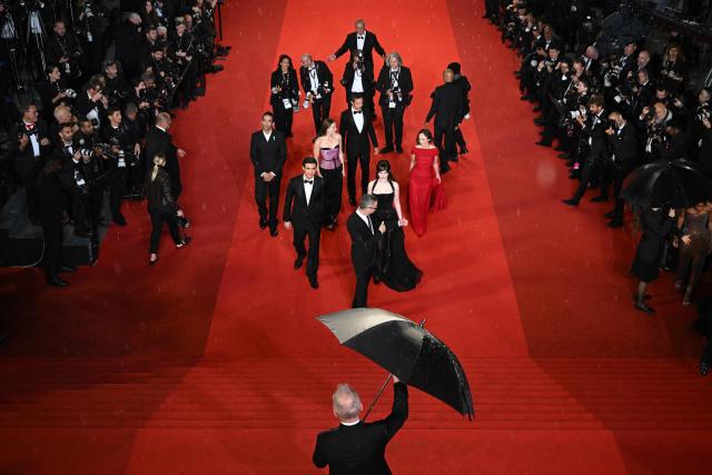 Cannes film festival director Thierry Fremaux holds an umbrella as the cast arrives for the screening of the film "Her Private Hell" at the 79th edition of the Cannes Film Festival in Cannes, southern France on May 18, 2026. (Photo by Antonin THUILLIER / AFP)