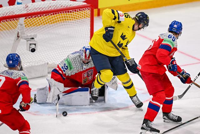 Czech Republic's goalkeeper #32 Josef Korenar (C) deflect a puck next to Sweden's forward #15 Jack Berglund (2ndR) during the Group B ice hockey match between Sweden and Czech Republic at the IIHF Ice Hockey Men's World Championship at BFC Arena in Fribourg on May 18, 2026. (Photo by Fabrice COFFRINI / AFP)