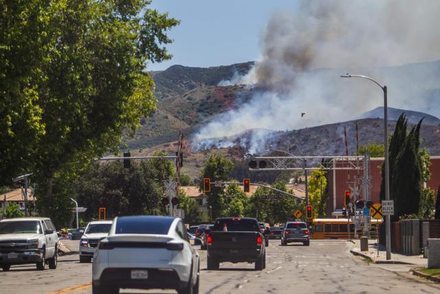 Cars negotiate Sycamore Drive as the Sandy Fire burns in the hills of Simi Valley, California, on May 18, 2026. About 24,000 people in Simi Valley, 40 miles northwest of Los Angeles, are under mandatory evacuation orders as the Sandy Fire is "spreading dangerously fast" according to fire officials. (Photo by Apu GOMES / AFP)