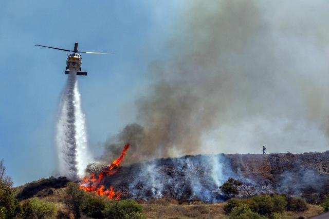 A Ventura County Fire Department helicopter drops water to combat the Sandy Fire in Simi Valley, California, on May 18, 2026. About 24,000 people in Simi Valley, 40 miles northwest of Los Angeles, are under mandatory evacuation orders as the Sandy Fire is "spreading dangerously fast" according to fire officials. (Photo by Apu GOMES / AFP)