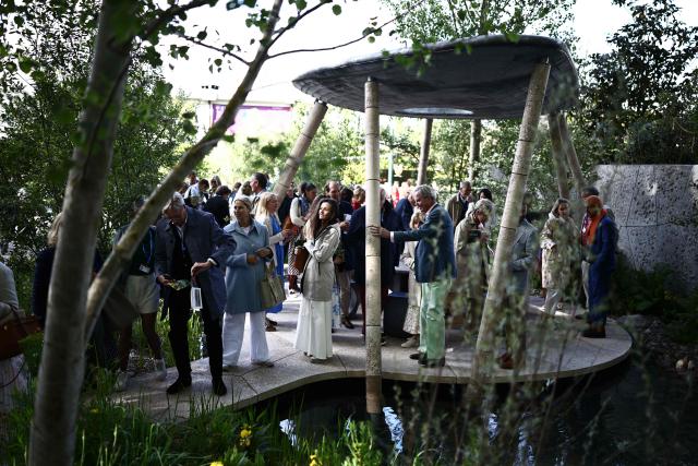 Visitors enjoy the Eden Project's "Bring Me Sunshine Garden" on the press day ahead of the 2026 RHS Chelsea Flower Show in London on May 18, 2026. With an eye on sustainability, the Bring Me Sunshine garden has been designed as part of the UK's second Eden Project to be opened in late 2028 in northwestern Morecambe. (Photo by Henry Nicholls / AFP)