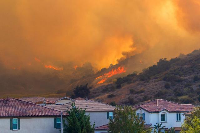 The Sandy Fire rages on a hill behind houses at a residential area in Simi Valley, California, on May 18, 2026. About 24,000 people in Simi Valley, 40 miles northwest of Los Angeles, are under mandatory evacuation orders as the Sandy Fire is "spreading dangerously fast" according to fire officials. (Photo by Apu GOMES / AFP)