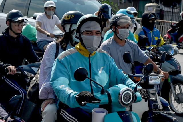 (FILES) A motorist rides a Vinfast electric motorbike along a street in Hanoi on May 13, 2026. Millions of exhaust-belching motorbikes zip through Hanoi's narrow streets every day fuelling its chronic air pollution, but authorities have backtracked from an ambitious plan to ban them in favour of electric two-wheelers. (Photo by Nhac NGUYEN / AFP) / To go with 'VIETNAM-CLIMATE-POLLUTION-TRANSPORT,FOCUS' by Tran Thi Minh Ha and Lam Nguyen)