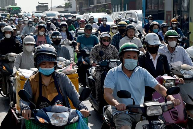 (FILES) People ride motorbikes and scooters along a street in Hanoi on May 13, 2026. Millions of exhaust-belching motorbikes zip through Hanoi's narrow streets every day fuelling its chronic air pollution, but authorities have backtracked from an ambitious plan to ban them in favour of electric two-wheelers. (Photo by Nhac NGUYEN / AFP) / To go with 'VIETNAM-CLIMATE-POLLUTION-TRANSPORT,FOCUS' by Tran Thi Minh Ha and Lam Nguyen)