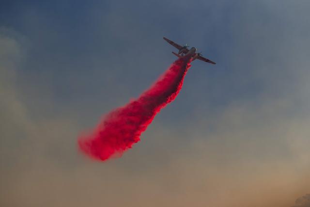 CORRECTION / A Cal Fire aircraft drops fire retardant on the Sandy Fire as it burns in the hills near a residential area in Simi Valley, California on May 18, 2026. A brush fire broke out May 15 in the suburbs of Los Angeles, spreading rapidly and prompting authorities to issue evacuation orders for thousands of residents. Dubbed the Sandy Fire, the blaze broke out late morning in Simi Valley, a city of roughly 125,000 residents about 40 miles (60 kilometers) northwest of downtown Los Angeles. (Photo by Apu GOMES / AFP) / The erroneous mention[s] appearing in the metadata of this photo by Apu GOMES has been modified in AFP systems in the following manner: [May 18] instead of [May 15]. Please immediately remove the erroneous mention[s] from all your online services and delete it (them) from your servers. If you have been authorized by AFP to distribute it (them) to third parties, please ensure that the same actions are carried out by them. Failure to promptly comply with these instructions will entail liability on your part for any continued or post notification usage. Therefore we thank you very much for all your attention and prompt action. We are sorry for the inconvenience this notification may cause and remain at your disposal for any further information you may require.