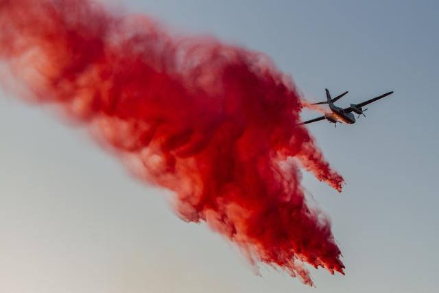 CORRECTION / A Cal Fire aircraft drops fire retardant on the Sandy Fire as it burns in the hills near a residential area in Simi Valley, California on May 18, 2026. A brush fire broke out May 15 in the suburbs of Los Angeles, spreading rapidly and prompting authorities to issue evacuation orders for thousands of residents. Dubbed the Sandy Fire, the blaze broke out late morning in Simi Valley, a city of roughly 125,000 residents about 40 miles (60 kilometers) northwest of downtown Los Angeles. (Photo by Apu GOMES / AFP) / The erroneous mention[s] appearing in the metadata of this photo by Apu GOMES has been modified in AFP systems in the following manner: [May 18] instead of [May 15]. Please immediately remove the erroneous mention[s] from all your online services and delete it (them) from your servers. If you have been authorized by AFP to distribute it (them) to third parties, please ensure that the same actions are carried out by them. Failure to promptly comply with these instructions will entail liability on your part for any continued or post notification usage. Therefore we thank you very much for all your attention and prompt action. We are sorry for the inconvenience this notification may cause and remain at your disposal for any further information you may require.