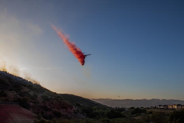 CORRECTION / A Cal Fire aircraft drops fire retardant on the Sandy Fire as it burns in the hills near a residential area in Simi Valley, California on May 18, 2026. A brush fire broke out May 15 in the suburbs of Los Angeles, spreading rapidly and prompting authorities to issue evacuation orders for thousands of residents. Dubbed the Sandy Fire, the blaze broke out late morning in Simi Valley, a city of roughly 125,000 residents about 40 miles (60 kilometers) northwest of downtown Los Angeles. (Photo by Apu GOMES / AFP) / The erroneous mention[s] appearing in the metadata of this photo by Apu GOMES has been modified in AFP systems in the following manner: [May 18] instead of [May 15]. Please immediately remove the erroneous mention[s] from all your online services and delete it (them) from your servers. If you have been authorized by AFP to distribute it (them) to third parties, please ensure that the same actions are carried out by them. Failure to promptly comply with these instructions will entail liability on your part for any continued or post notification usage. Therefore we thank you very much for all your attention and prompt action. We are sorry for the inconvenience this notification may cause and remain at your disposal for any further information you may require.