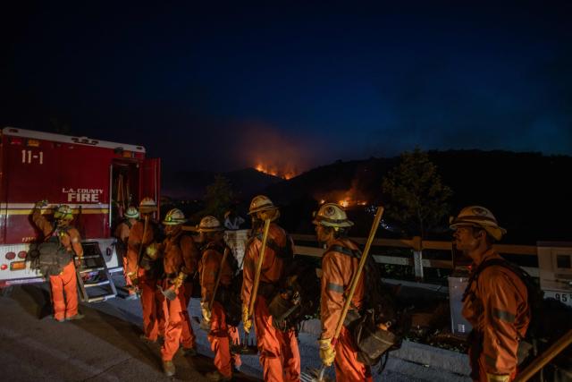 Inmate firefighters walk back to their fire truck after combating the Sandy Fire in Simi Valley, California on May 18, 2026. A brush fire broke out May 15 in the suburbs of Los Angeles, spreading rapidly and prompting authorities to issue evacuation orders for thousands of residents. Dubbed the Sandy Fire, the blaze broke out late morning in Simi Valley, a city of roughly 125,000 residents about 40 miles (60 kilometers) northwest of downtown Los Angeles. (Photo by Apu GOMES / AFP)