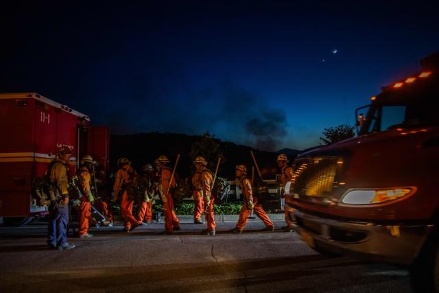 Inmate firefighters walk back to their fire truck after combating the Sandy Fire in Simi Valley, California on May 18, 2026. A brush fire broke out May 15 in the suburbs of Los Angeles, spreading rapidly and prompting authorities to issue evacuation orders for thousands of residents. Dubbed the Sandy Fire, the blaze broke out late morning in Simi Valley, a city of roughly 125,000 residents about 40 miles (60 kilometers) northwest of downtown Los Angeles. (Photo by Apu GOMES / AFP)