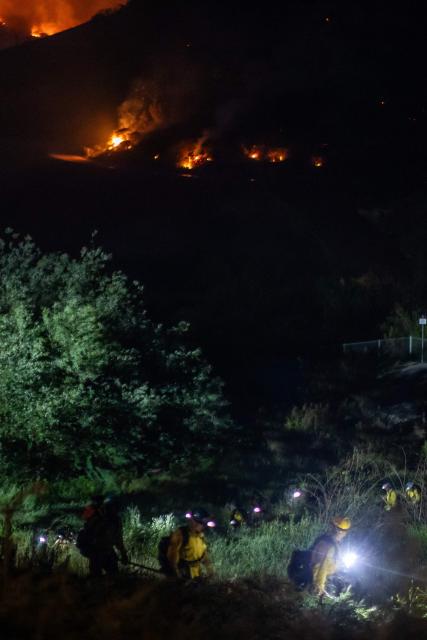 Firefighters walk back to their fire truck as the Sandy Fire continues to burn in the hills of Simi Valley, California on May 18, 2026. A brush fire broke out May 15 in the suburbs of Los Angeles, spreading rapidly and prompting authorities to issue evacuation orders for thousands of residents. Dubbed the Sandy Fire, the blaze broke out late morning in Simi Valley, a city of roughly 125,000 residents about 40 miles (60 kilometers) northwest of downtown Los Angeles. (Photo by Apu GOMES / AFP) / The erroneous mention[s] appearing in the metadata of this photo by Apu GOMES has been modified in AFP systems in the following manner: [May 18] instead of [May 15]. Please immediately remove the erroneous mention[s] from all your online services and delete it (them) from your servers. If you have been authorized by AFP to distribute it (them) to third parties, please ensure that the same actions are carried out by them. Failure to promptly comply with these instructions will entail liability on your part for any continued or post notification usage. Therefore we thank you very much for all your attention and prompt action. We are sorry for the inconvenience this notification may cause and remain at your disposal for any further information you may require.
