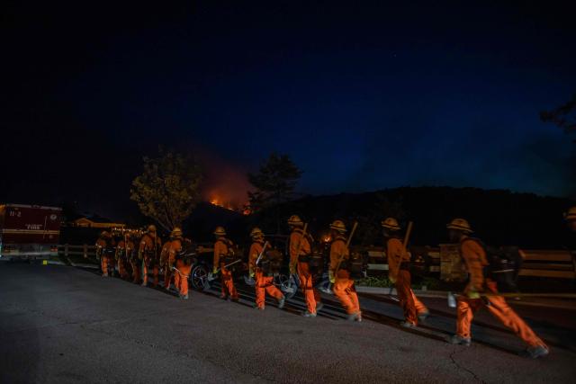 Inmate firefighters walk back to their fire truck after combating the Sandy Fire in Simi Valley, California on May 18, 2026. A brush fire broke out May 15 in the suburbs of Los Angeles, spreading rapidly and prompting authorities to issue evacuation orders for thousands of residents. Dubbed the Sandy Fire, the blaze broke out late morning in Simi Valley, a city of roughly 125,000 residents about 40 miles (60 kilometers) northwest of downtown Los Angeles. (Photo by Apu GOMES / AFP)