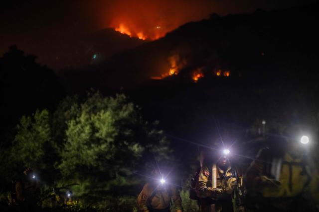 Firefighters walk back to their fire truck as the Sandy Fire continues to burn in the hills of Simi Valley, California on May 18, 2026. A brush fire broke out May 15 in the suburbs of Los Angeles, spreading rapidly and prompting authorities to issue evacuation orders for thousands of residents. Dubbed the Sandy Fire, the blaze broke out late morning in Simi Valley, a city of roughly 125,000 residents about 40 miles (60 kilometers) northwest of downtown Los Angeles. (Photo by Apu GOMES / AFP) / The erroneous mention[s] appearing in the metadata of this photo by Apu GOMES has been modified in AFP systems in the following manner: [May 18] instead of [May 15]. Please immediately remove the erroneous mention[s] from all your online services and delete it (them) from your servers. If you have been authorized by AFP to distribute it (them) to third parties, please ensure that the same actions are carried out by them. Failure to promptly comply with these instructions will entail liability on your part for any continued or post notification usage. Therefore we thank you very much for all your attention and prompt action. We are sorry for the inconvenience this notification may cause and remain at your disposal for any further information you may require.
