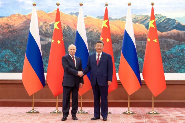 In this pool photograph distributed by the Russian state agency Sputnik, Russia's President Vladimir Putin (L) shakes hands with China's President Xi Jinping during a meeting in Beijing on May 20, 2026. (Photo by Maxim Stulov / POOL / AFP)