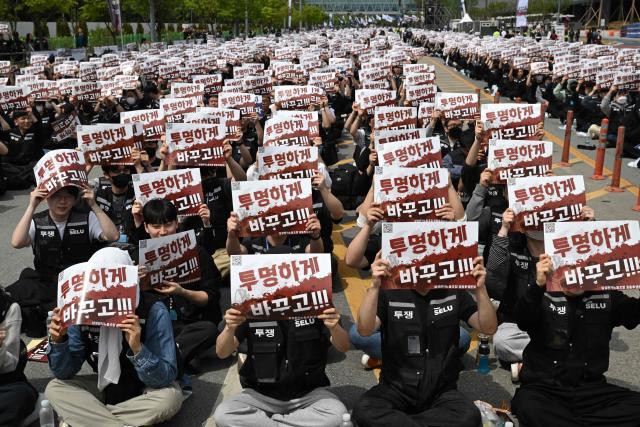 (FILES) Members of the Samsung Electronics labour union hold signs reading "Change it to be transparent!" as they stage a mass rally demanding the removal of a cap on performance bonuses, outside the company's foundry and semiconductor factory in Pyeongtaek on April 23, 2026. The labour union at South Korean chip giant Samsung Electronics said on May 20, 2026 it would launch a planned strike after talks over bonus payouts collapsed. (Photo by Jung Yeon-je / AFP)