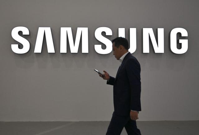 (FILES) A visitor walks past the logo of Samsung Electronics during the Korea Electronics Show 2025 at the COEX convention and exhibition centre in Seoul on October 22, 2025. The labour union at South Korean chip giant Samsung Electronics said on May 20, 2026 it would launch a planned strike after talks over bonus payouts collapsed. (Photo by Jung Yeon-je / AFP)