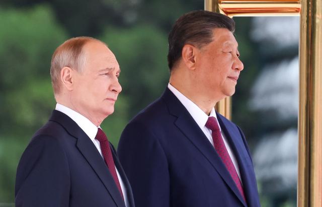 In this pool photograph distributed by the Russian state agency Sputnik, Russia's President Vladimir Putin (L) and China's President Xi Jinping take part in a welcome ceremony at the Great Hall of the People in Beijing on May 20, 2026. (Photo by Alexander KAZAKOV / POOL / AFP)