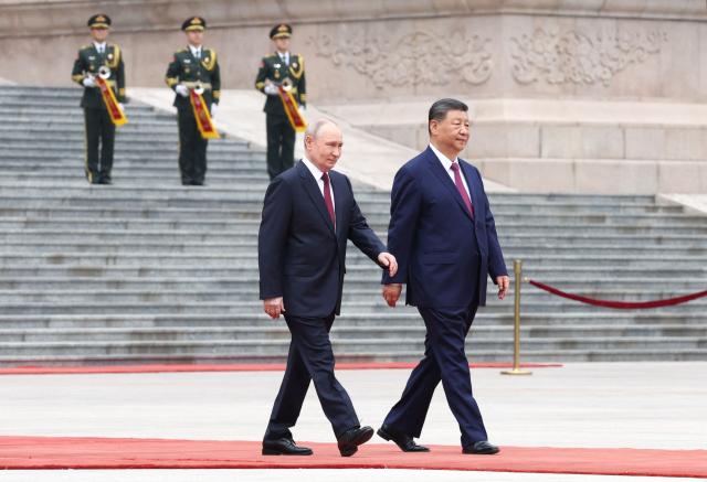 In this pool photograph distributed by the Russian state agency Sputnik, Russia's President Vladimir Putin (L) and China's President Xi Jinping walk together during a welcome ceremony at the Great Hall of the People in Beijing on May 20, 2026. (Photo by Alexander KAZAKOV / POOL / AFP)