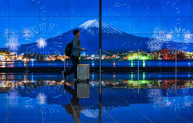 A traveller walks past an image of Mount Fuji in the arrivals terminal at Haneda Airport in Tokyo on May 20, 2026. (Photo by Kazuhiro NOGI / AFP)