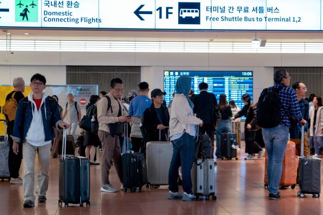 Travellers make their way in the arrivals terminal at Haneda Airport in Tokyo on May 20, 2026. (Photo by Kazuhiro NOGI / AFP)