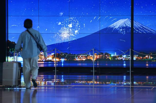 A traveller walks past an image of Mount Fuji in the arrivals terminal at Haneda Airport in Tokyo on May 20, 2026. (Photo by Kazuhiro NOGI / AFP)