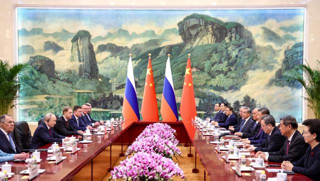 In this pool photograph distributed by the Russian state agency Sputnik, Russia's President Vladimir Putin (2nd L) and China's President Xi Jinping (4th R) take part in a meeting in Beijing on May 20, 2026. (Photo by Alexander KAZAKOV / POOL / AFP)