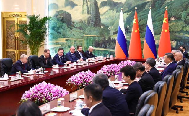 In this pool photograph distributed by the Russian state agency Sputnik, Russia's President Vladimir Putin (L) and China's President Xi Jinping (2nd R) take part in a meeting in Beijing on May 20, 2026. (Photo by Alexander KAZAKOV / POOL / AFP)