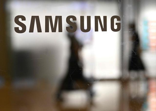 The logo of Samsung Electronics is displayed on a glass door at the company's Seocho building in Seoul on May 20, 2026. A planned strike at South Korean chip giant Samsung Electronics will go ahead from May 21, its union said, after talks on bonus payouts collapsed, raising concerns over a disruption to the country's key semiconductor industry. (Photo by Jung Yeon-je / AFP)