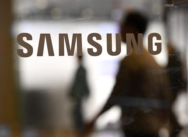 The logo of Samsung Electronics is displayed on a glass door at the company's Seocho building in Seoul on May 20, 2026. A planned strike at South Korean chip giant Samsung Electronics will go ahead from May 21, its union said, after talks on bonus payouts collapsed, raising concerns over a disruption to the country's key semiconductor industry. (Photo by Jung Yeon-je / AFP)