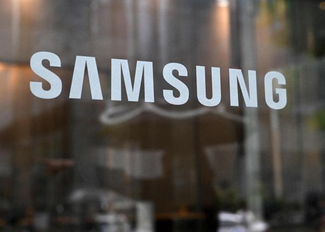 The logo of Samsung Electronics is displayed on a glass door at the company's Seocho building in Seoul on May 20, 2026. A planned strike at South Korean chip giant Samsung Electronics will go ahead from May 21, its union said, after talks on bonus payouts collapsed, raising concerns over a disruption to the country's key semiconductor industry. (Photo by Jung Yeon-je / AFP)