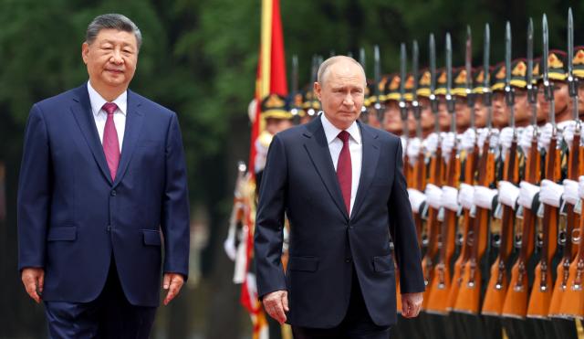 In this pool photograph distributed by the Russian state agency Sputnik, Russia's President Vladimir Putin (C) and China's President Xi Jinping (L) inspect a honour guard during a welcome ceremony at the Great Hall of the People in Beijing on May 20, 2026. (Photo by Alexander KAZAKOV / POOL / AFP)