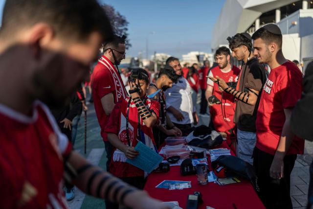 Hapoel Tel Aviv fans wrap their hands with tefillin (small black leather boxes containing Hebrew parchment scrolls with verses from the Torah) as they pray ahead of a match against Beitar Jerusalem at Bloomfield Stadium in Tel Aviv on May 6, 2026. (Photo by Ilia YEFIMOVICH / AFP)
