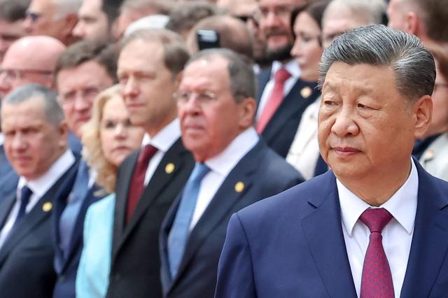 In this pool photograph distributed by the Russian state agency Sputnik, Chinese President Xi Jinping (R) walks past members of the Russian delegation during a welcome ceremony for Russia's President Vladimir Putin (not pictured) at the Great Hall of the People in Beijing on May 20, 2026. (Photo by Alexander KAZAKOV / POOL / AFP)