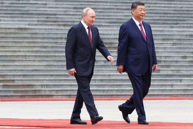 In this pool photograph distributed by the Russian state agency Sputnik, Russia's President Vladimir Putin and China's President Xi Jinping (R) inspect a honour guard during a welcome ceremony at the Great Hall of the People in Beijing on May 20, 2026. (Photo by Alexander KAZAKOV / POOL / AFP)