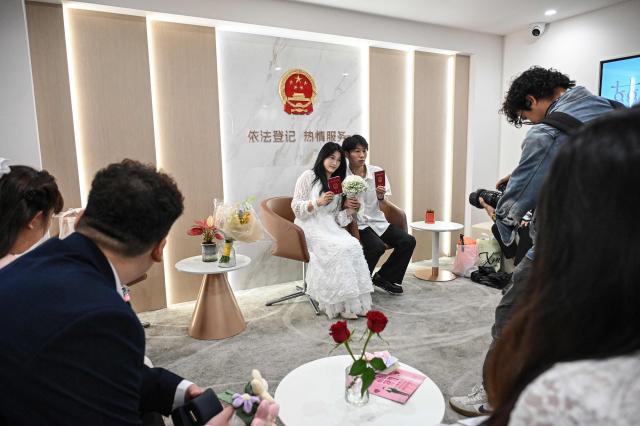 A newly-wedded couple pose for photos at a marriage registry in Shanghai on May 20, 2026, known as "520 Day", as the numbers sound like "I love you" in Chinese. (Photo by Jade GAO / AFP)