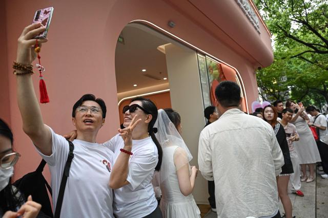 Couples queue outside a marriage registry to collect their certificates in Shanghai on May 20, 2026, known as "520 Day", as the numbers sound like "I love you" in Chinese. (Photo by Jade GAO / AFP)