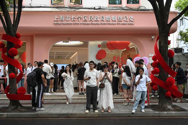 Couples queue outside a marriage registry to collect their certificates in Shanghai on May 20, 2026, known as "520 Day", as the numbers sound like "I love you" in Chinese. (Photo by Jade GAO / AFP)