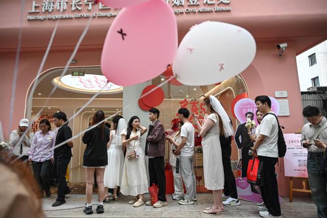 Couples queue outside a marriage registry to collect their certificates in Shanghai on May 20, 2026, known as "520 Day", as the numbers sound like "I love you" in Chinese. (Photo by Jade GAO / AFP)