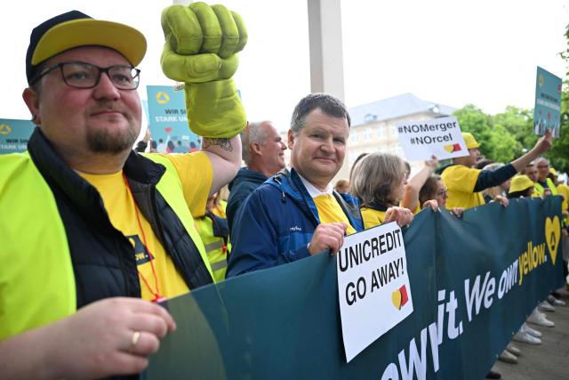 Employees demonstrate in front of the venue where is taking place the annual general meeting of Germany's Commerzbank bank, on May 20, 2026 in Wiesbaden, western Germany. Commerzbank plans to fend off a hostile takeover by Italy's UniCredit with job cuts and higher profit targets. The Frankfurt-based bank announced earlier in May 2026 that it will cut a further 3,000 jobs by 2030 and raised its business targets. Lower costs and higher profits are driving up the share price, making a potential takeover more expensive. (Photo by Kirill KUDRYAVTSEV / AFP)