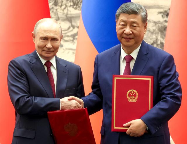 In this pool photograph distributed by the Russian state agency Sputnik, Russia's President Vladimir Putin and China's President Xi Jinping shake hands during a signing ceremony following their talks in Beijing on May 20, 2026. (Photo by Alexander KAZAKOV / POOL / AFP)