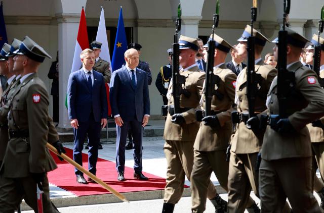 Poland's Prime Minister Donald Tusk (C-R) and Hungary's Prime Minister Peter Magyar (C-L) review a military honor guard in Warsaw, Poland, on May 20, 2026. Hungary's new Prime Minister Peter Magyar is on a two-day visit to Poland for his first official trip abroad, hoping to mark his country's re-alignment with the European Union after years of open conflict under his predecessor. (Photo by Wojtek RADWANSKI / AFP)