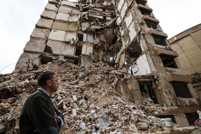 Wael Sabbagh, who lost his mother and brother when their house in Beirut’s Tallet el-Khayat, an affluent residential neighborhood was struck by an Israeli strike in April, stands in front of the remains of the building on May 18, 2026. Standing in front of their parents’ building, which was destroyed by an Israeli strike in Beirut, Ghida Krisht and Wael Sabbagh make a solemn vow: to seek justice through international bodies for their slain families. On this April 8, the “Black Wednesday” when massive Israeli strikes killed more than 350 people in Lebanon according to authorities, Ghida lost her parents and a close relative, and Wael lost his mother and brother. The final strike on Beirut that day targeted the building where they had lived for some fifty years in Tallet el-Khayat, an affluent residential neighborhood where they believed they were safe. (Photo by Anwar AMRO / AFP)