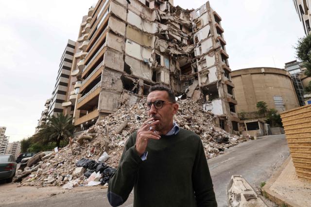 Wael Sabbagh, who lost his mother and brother when their house in Beirut’s Tallet el-Khayat, an affluent residential neighborhood was struck by an Israeli strike in April, stands in front of the remains of the building on May 18, 2026. Standing in front of their parents’ building, which was destroyed by an Israeli strike in Beirut, Ghida Krisht and Wael Sabbagh make a solemn vow: to seek justice through international bodies for their slain families. On this April 8, the “Black Wednesday” when massive Israeli strikes killed more than 350 people in Lebanon according to authorities, Ghida lost her parents and a close relative, and Wael lost his mother and brother. The final strike on Beirut that day targeted the building where they had lived for some fifty years in Tallet el-Khayat, an affluent residential neighborhood where they believed they were safe. (Photo by Anwar AMRO / AFP)